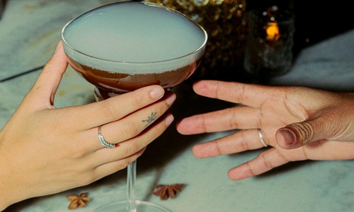 hands sharing a cocktail indoors