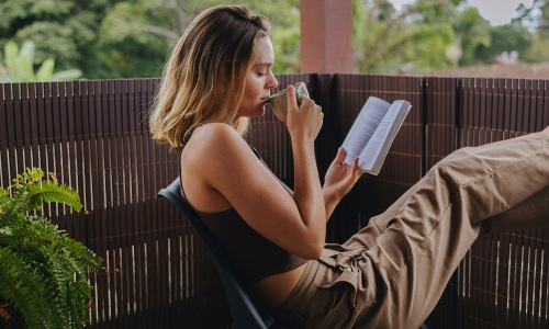 a woman drinking a coffee with a book in her hand