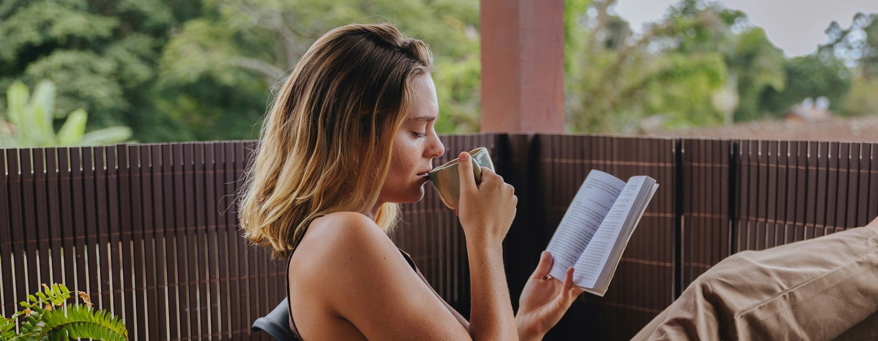 a woman drinking a coffee with a book in her hand