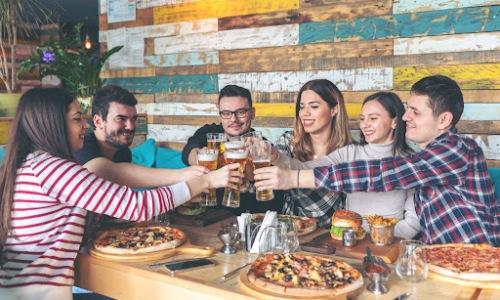 A group of friends sitting around a restaurant table enjoying food, drinks, and each other’s company